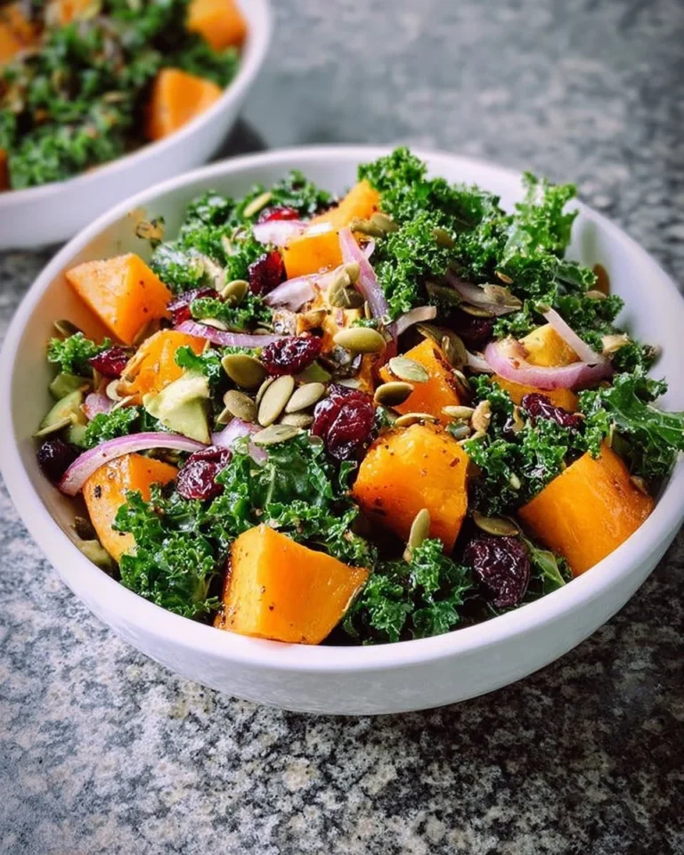 Butternut squash cranberry kale salad in a bowl, garnished with nuts.